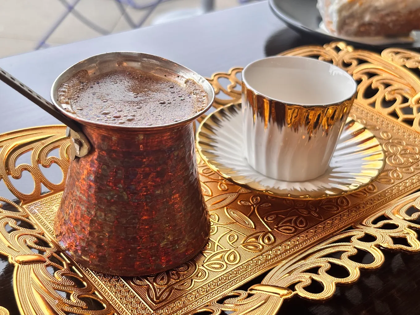 Turkish coffee brewed in a copper dallah, served with a gold-rimmed cup